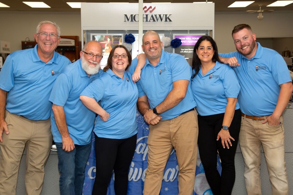 The My Dad's Flooring team posing together at their main office and showroom