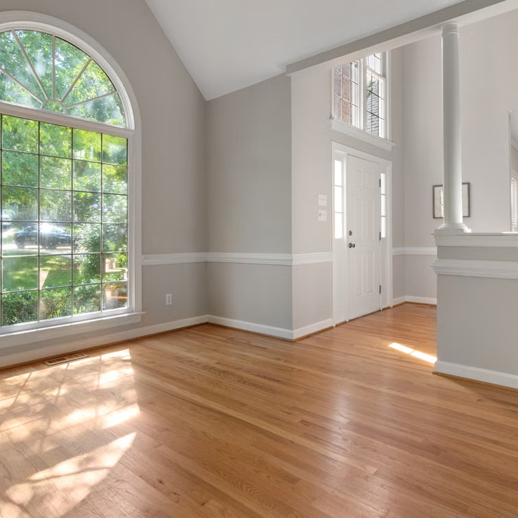 an empty room in a home with new hardwood floors.